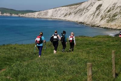 Walkers taking on the Isle of Wight Challenge as they trek beside cliffs on a coastal path
