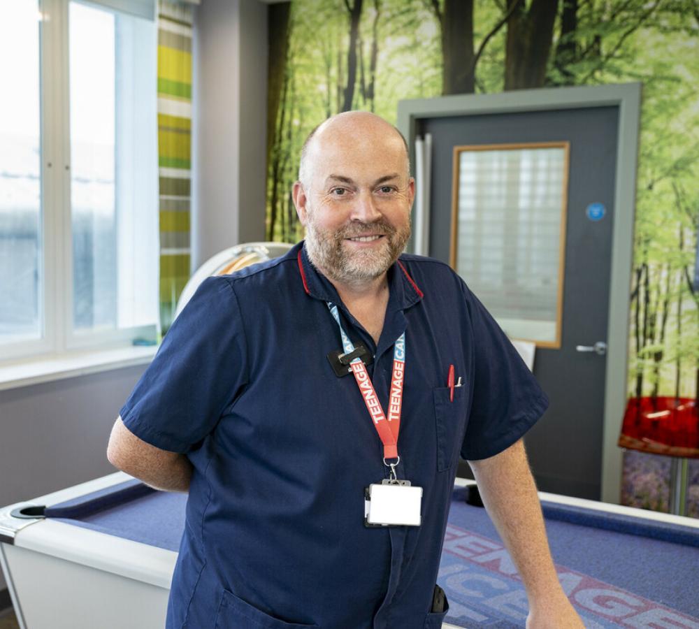 A Teenage Cancer Trust Nurse standing in a brightly decorated hospital room