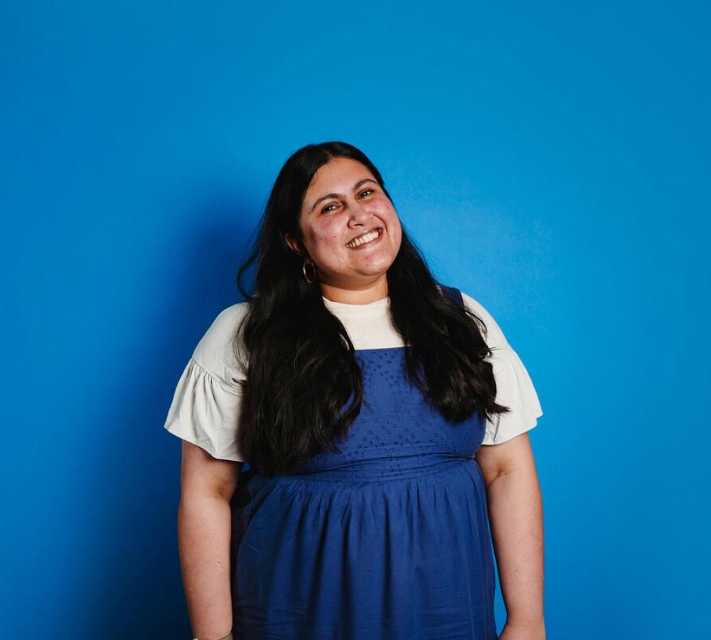 Tanya from Teenage Cancer Trust's Youth Advisory Group smiling against a blue background