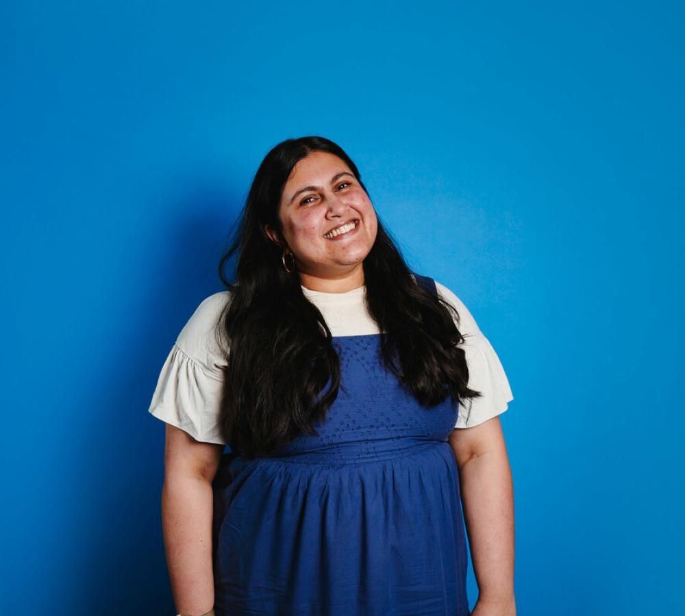Tanya from Teenage Cancer Trust's Youth Advisory Group smiling against a blue background