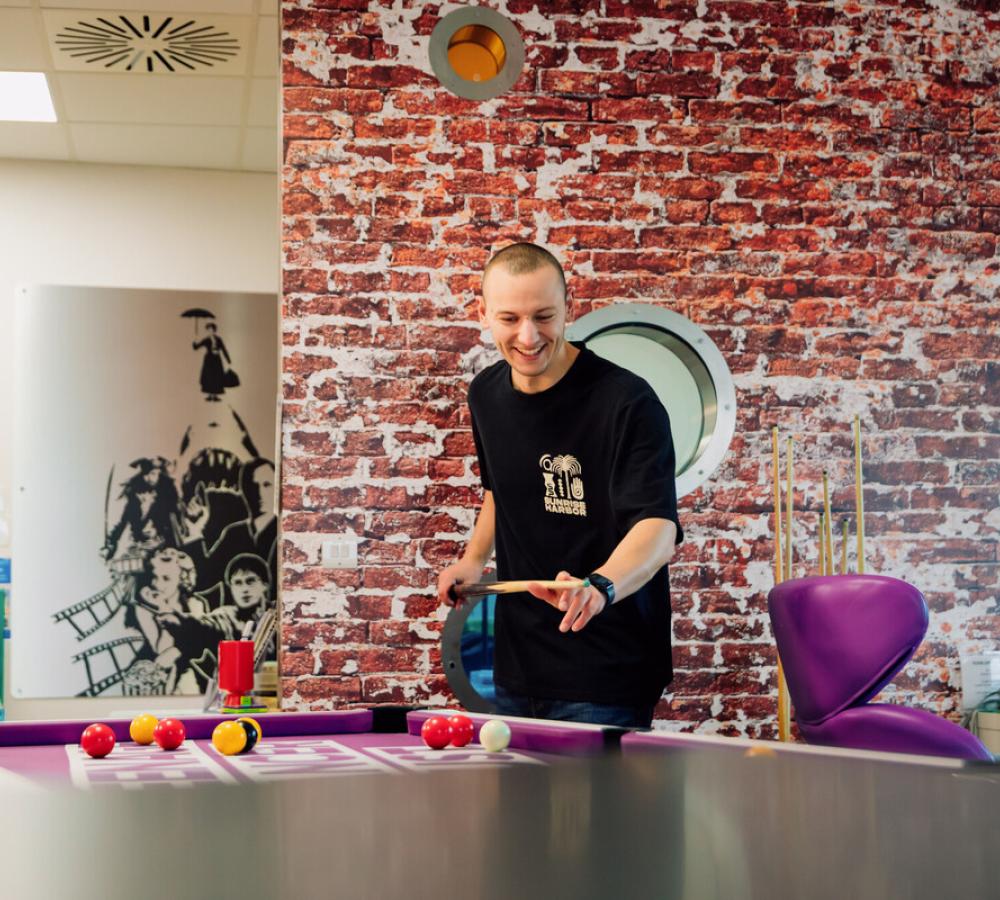 Young person playing pool on brightly coloured Teenage Cancer Trust unit