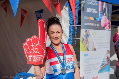 Teenage Cancer Trust Great Birmingham Run runner after event with their medal and a big foam finger