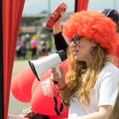Teenage Cancer Trust Great Mancher Run cheer team member with orange wif and megaphone