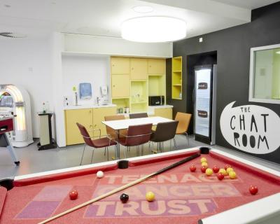 The games room at the Bristol Haematology and Oncology Centre with a pool table, jukebox and table with chairs