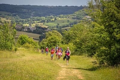 A group of walkers taking on the Cotswold Way Challenge walking up a hilly country path