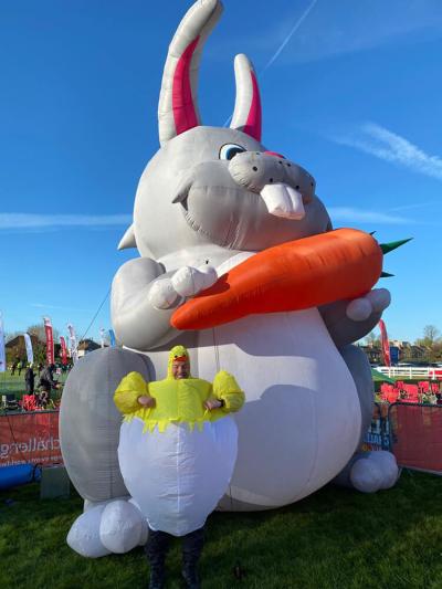 A man dressed as an Easter chick poses next to a giant Easter bunny at the Easter 50 Challenge