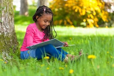 A young girl reading a book as part of a sponsored fundraising challenge for Teenage Cancer Trust