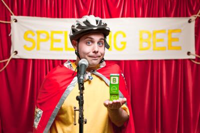 A man stood in front of a sign which says 'spelling bee'