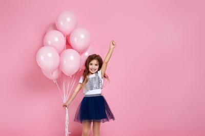 A little girl holding pink balloons on her birthday