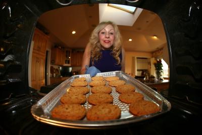 A baker removing cookies from an oven that will be sold at her Teenage Cancer Trust bake sale