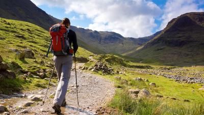 The back of a walker wearing a backpack who is trekking in hills to raise money for Teenage Cancer Trust