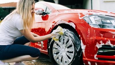 A woman cleaning a car as part of her community car washing to raise money for Teenage Cancer Trust