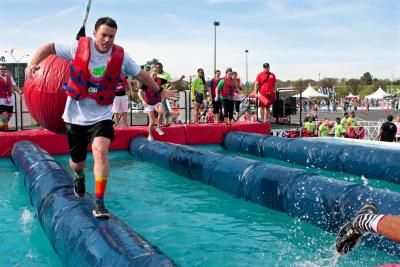 People taking on an inflatable obstacle course over water to raise money for Teenage Cancer Trust
