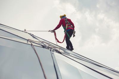 A fundraiser abseiling down a tall glass building as part of a challenge to raise money for Teenage Cancer Trust