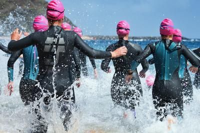 A group in wetsuits running into the sea as part of a cold water challenge to raise money for Teenage Cancer Trust