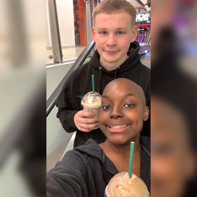 Yami taking a selfie out and about having a milkshake, showing her hair loss during cancer treatment. 