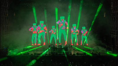 Chemical Brothers on stage with green laser lights and images of people in the back ground