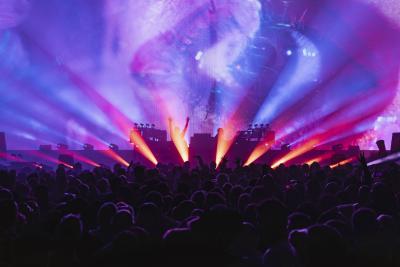 The Chemical Brothers at the Royal Albert Hall. Blue and red lights shine out from the stage through a hazy atmosphere, the crowd are in shadow but are dancing wildly. 