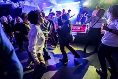 People dancing in front of a band on stage at a Teenage Cancer Trust event