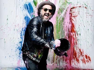The artist Mr Brainwash in a hat and sunglasses, laughing and holding a paint tin