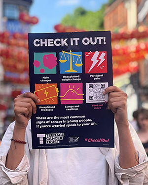 A poster about signs and symptoms, being held up by someone wearing a white top.