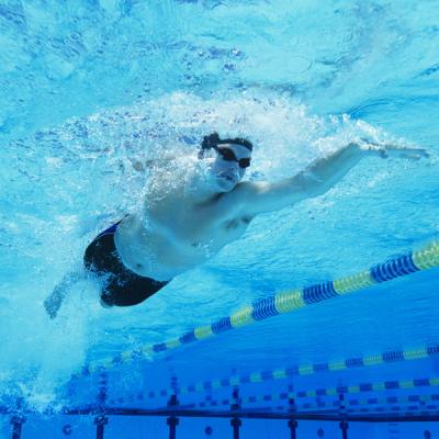 A person swimming in a swimming pool wearing a swim hat and goggles