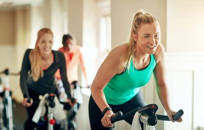 People on exercise bikes smiling and taking part in a spin class
