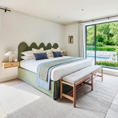 A large double bed with forest green linen and headboard in the main bedroom at the Omaze Million Pound House Draw house in the New Forest