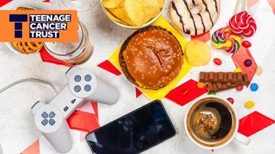 A table with sweet treats, coffee, a gaming controller, a burger and a phone on it