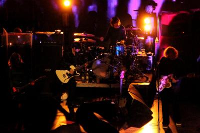 Members of My Bloody Valentine performing on a darkly lit stage