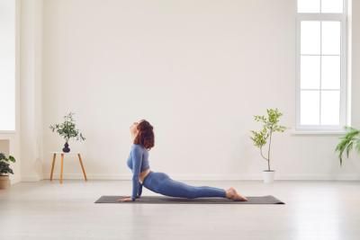 A person in a living room with plants doing Yoga