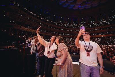 Abbie - wearing a floral dress - stands in the centre of other young people onstage at the Royal Albert Hall for the 'ultimate selfie moment'