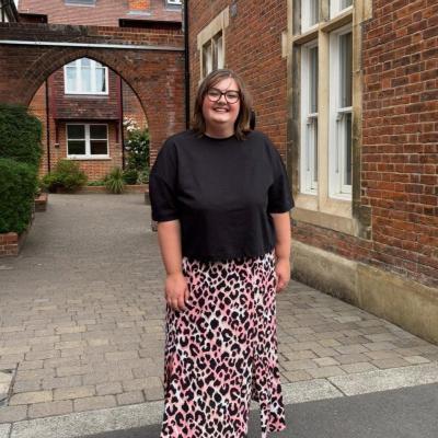 Abbie stands smiling in a red brick courtyard having finished cancer treatment