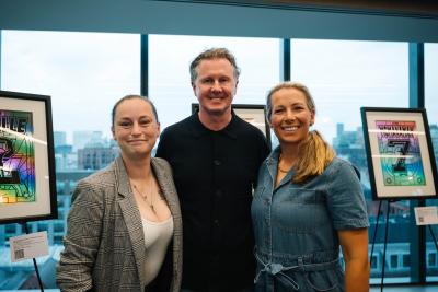 Shelbee Clarke, Steve McManaman and Rachel Brown-Finnis at the Fantasy Football print launch event, with two framed limited-edition signed prints visible in the background.