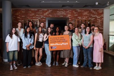 A group of young people holding a sign that says 'it's time to take action for young people with cancer'