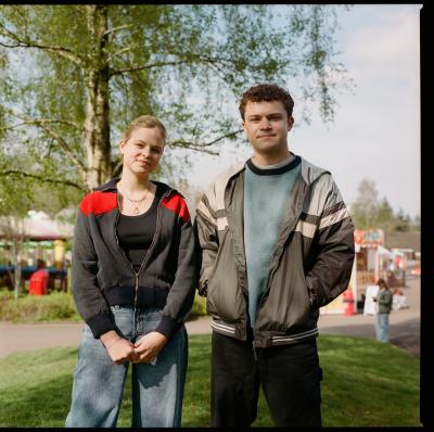A young woman wearing a grey and red hoodie and a young man wearing an olive hoodie