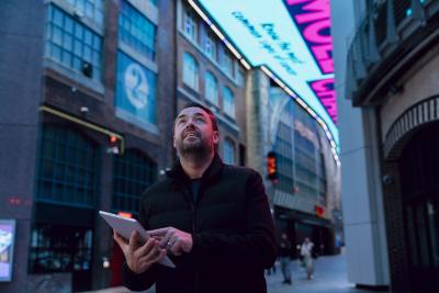 Jason Manford holding tablet looking at our ceiling digital display